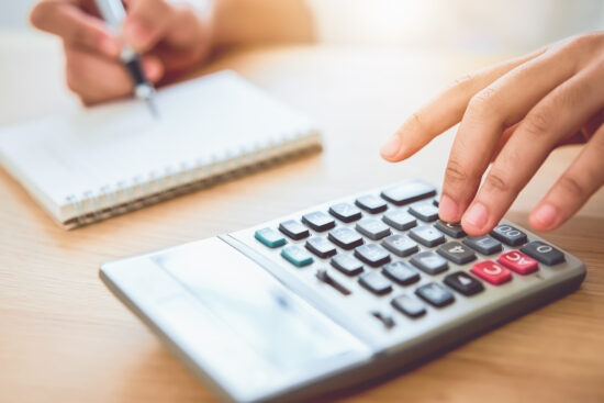 Woman holding and press calculator to calculate income expenses and plans for spending money on home office.