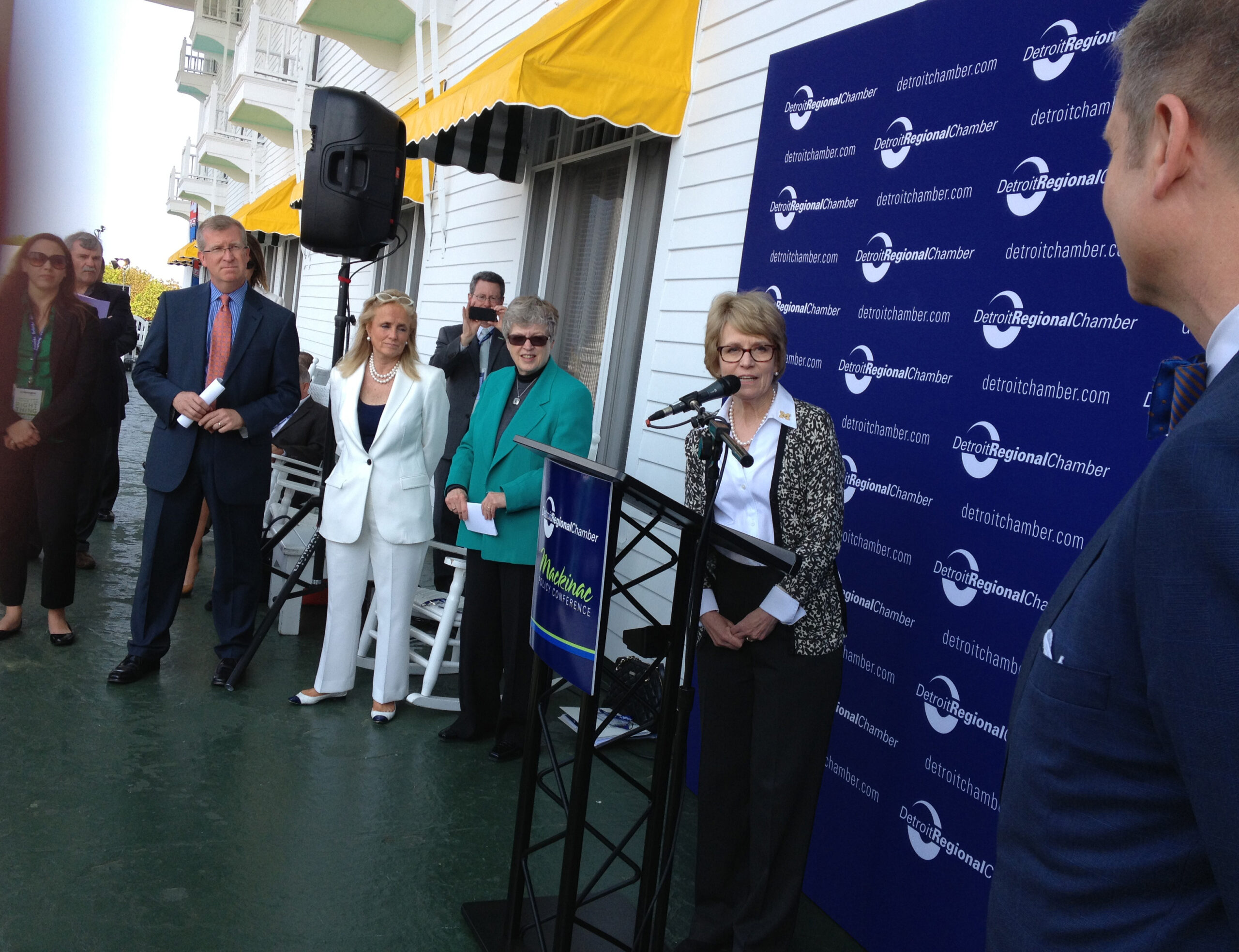 At news conference on porch of The Grand Hotel. (Left to right) Jeff Mason, Debbie Dingell,  MSU president Lou Anna Simon, Mary Sue Coleman, and Patrick Anderson. Image credit: John Russell, URC