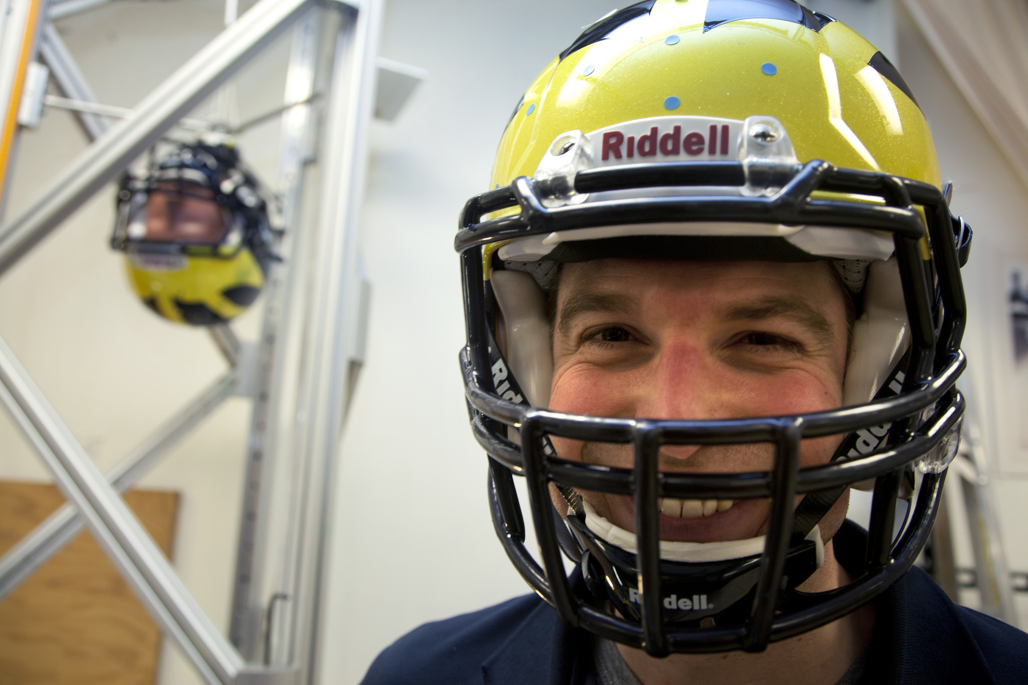   James Eckner, assistant professor of Physical Medicine and Rehabilitation poses in a Michigan football helmet as he gets ready to test helmet collision on a crash test dummy. Researchers in the Biomechanics Research Lab in the Department of Mechanical Engineering test new sensors that are designed to tell players and their coaches how hard they're hit. Such information can help in concussion diagnosis. Photo by Marcin Szczepanski, Michigan Engineering