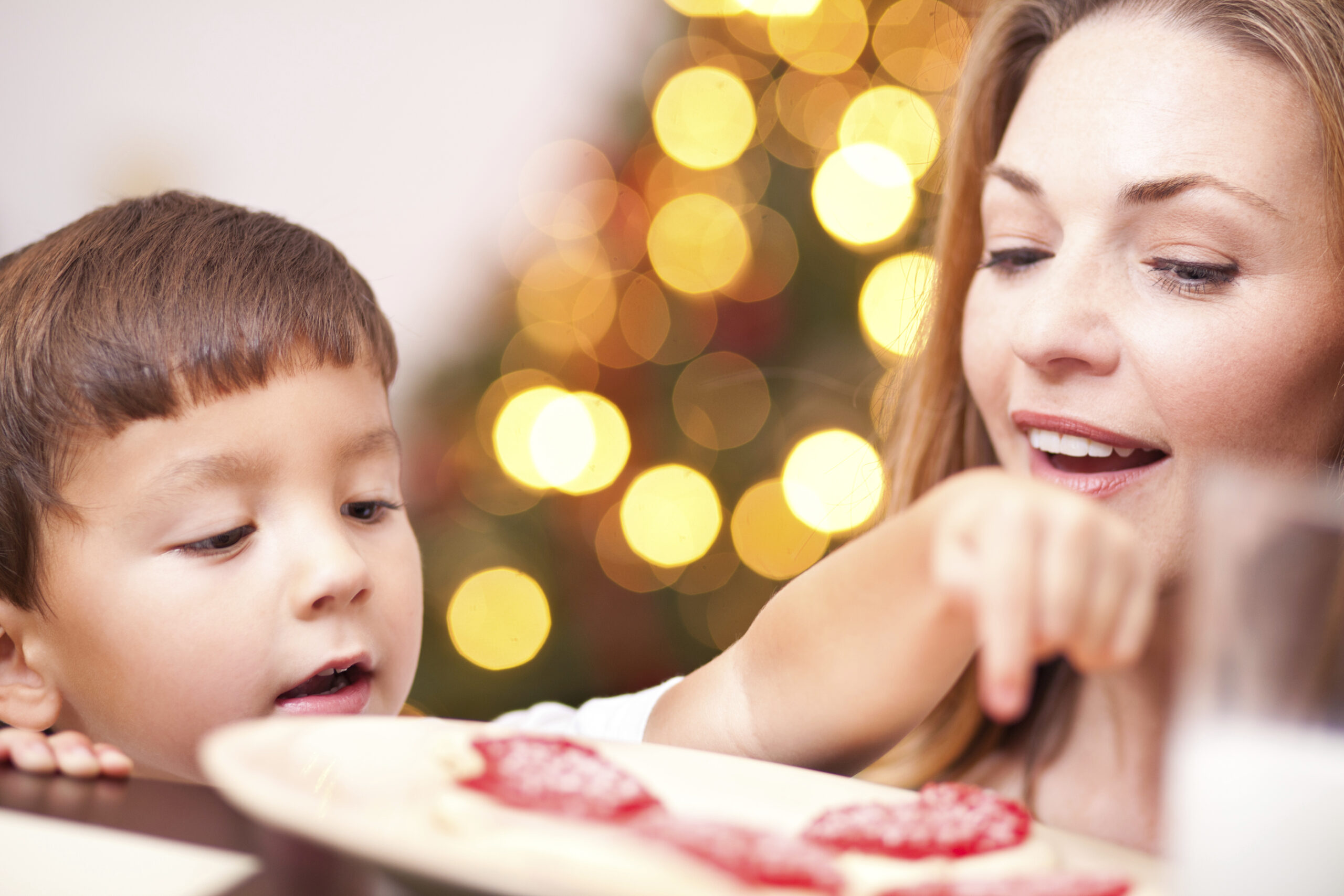 A little boy counts cookies while his mom looks on. (stock image)