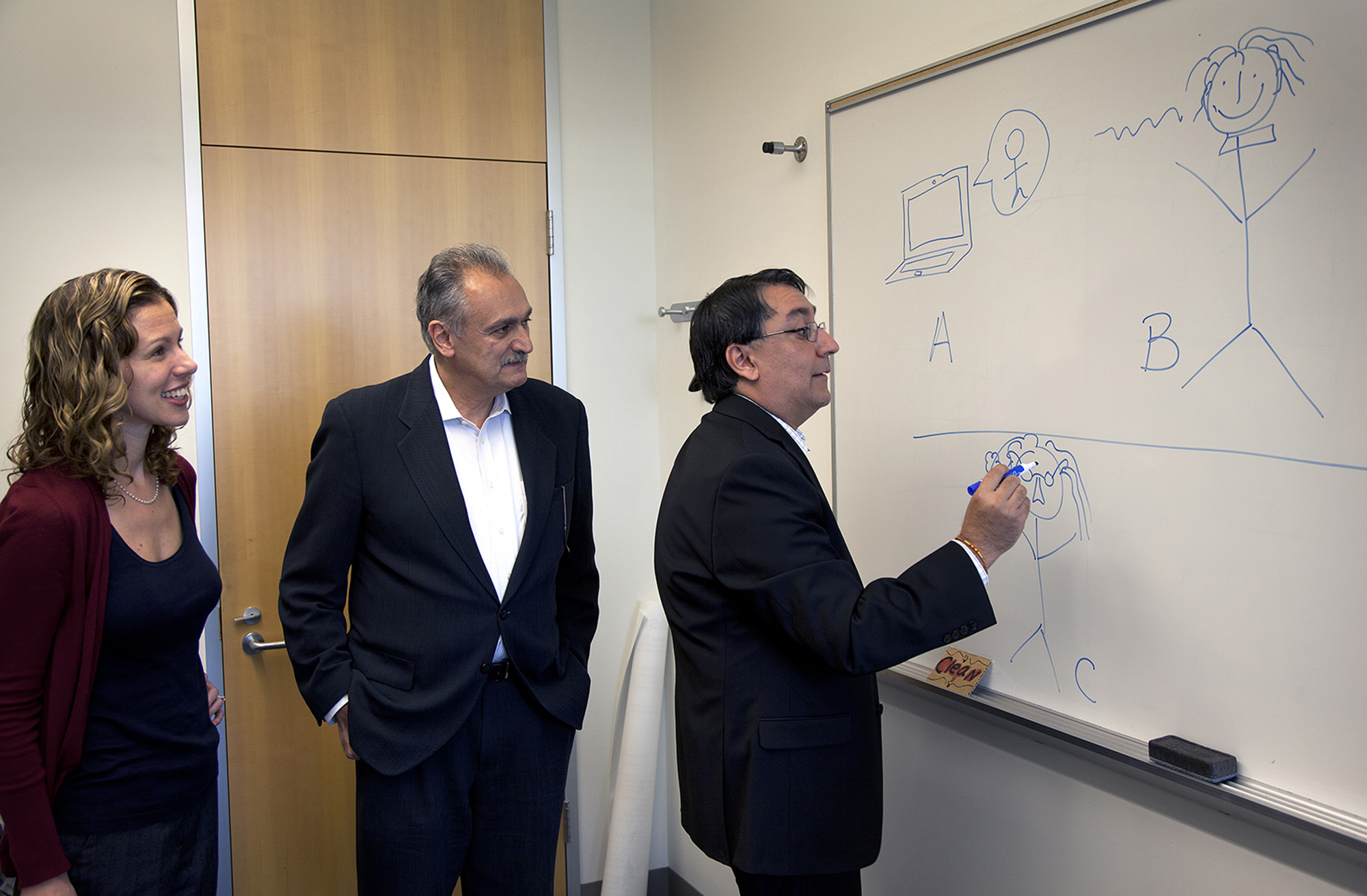 Satinder Singh Baveja, U-M professor of computer science and engineering, illustrates the Turing test, the famous test of machine intelligence developed by Alan Turing in 1950. For a computer to pass it, it must converse with a human so fluidly that the human believes the computer is a person. Also pictured are David Nahamoo, (center) IBM fellow and chief speech technology officer for IBM Watson, and Emily Mower Provost, U-M assistant professor of computer science and engineering. All are part of a team working to develop a truly conversational system that can assist in a student advisory capacity. Image credit: Joseph Xu