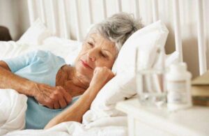 An older woman laying in bed with her eyes open. (stock image)