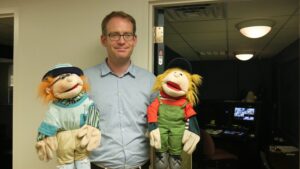 Felix Warneken, associate professor of psychology, poses with puppets used in the "trust experiment." Image credit: Sean Moore, Michigan News