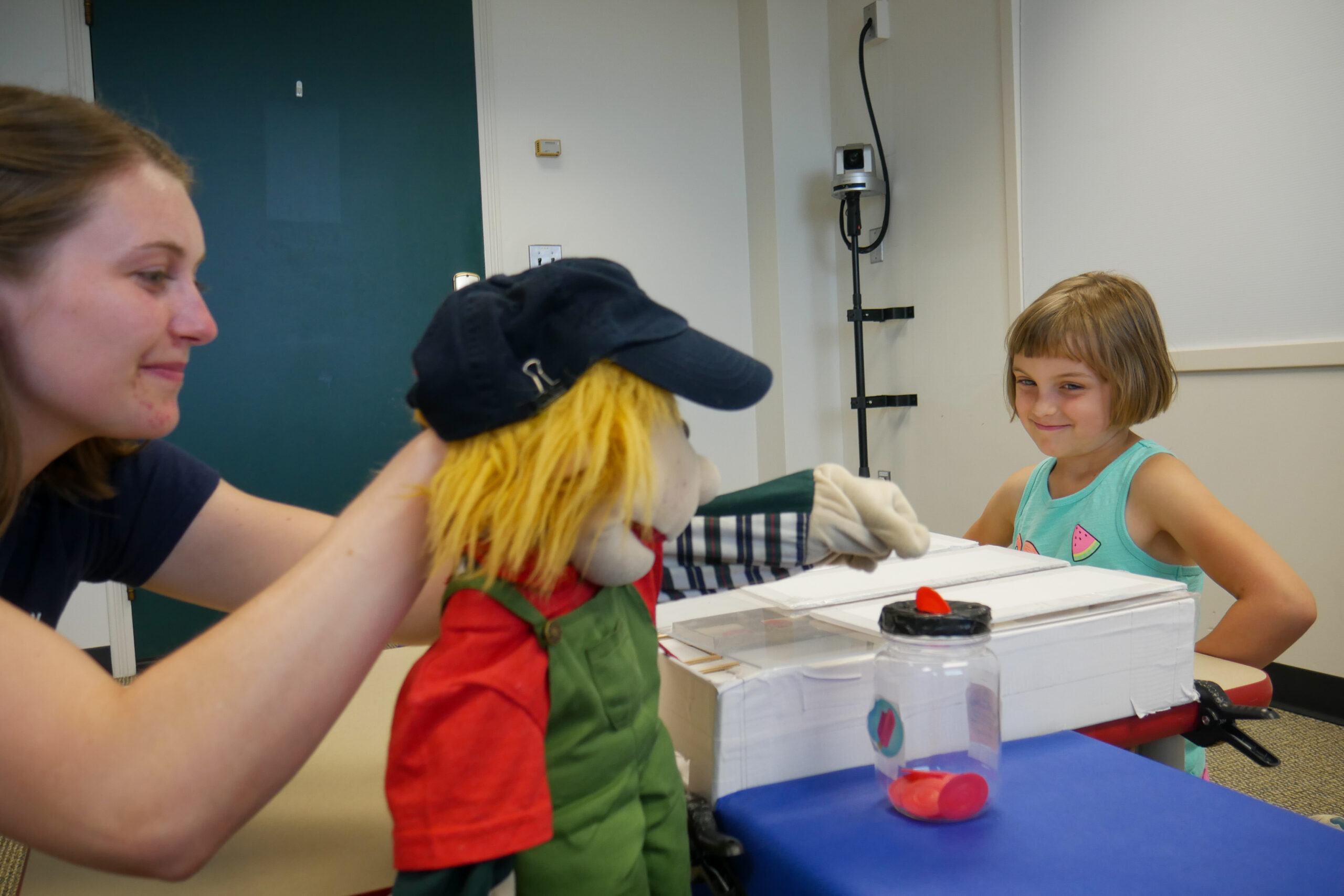 The puppet places several coins in its "bank" rather than sharing half of them with the girl, much to her dismay. Image credit: Sean Moore, Michigan News