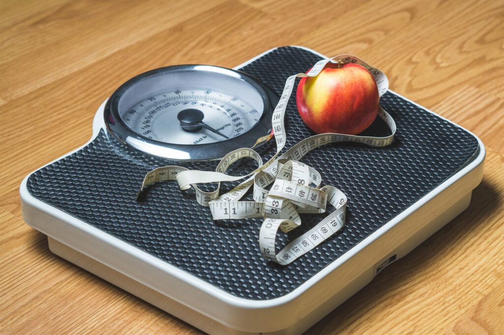 A scale, measuring tape and an apple. Image credit: Pixabay user, TeroVesalainen