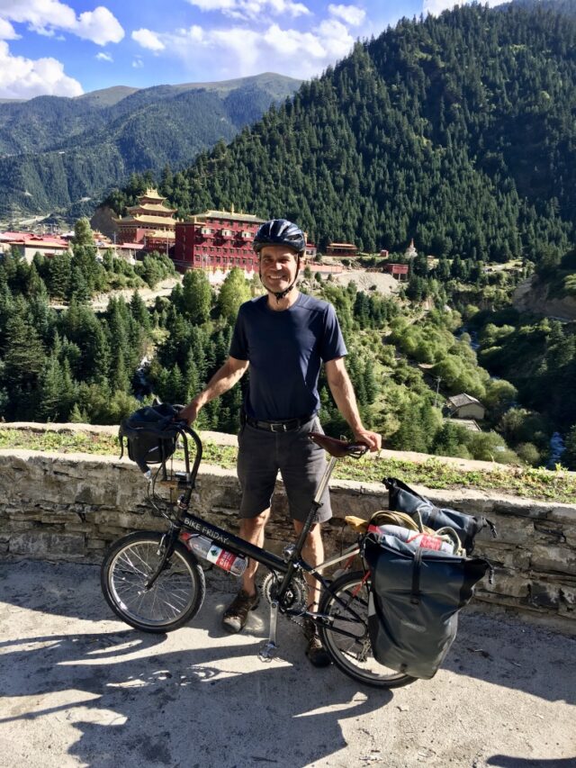 Stefan Koehler poses in summer 2019 in Sichuan Province, China, with a Tibetan monastery in the background. (Photo courtesy of Stefan Koehler)