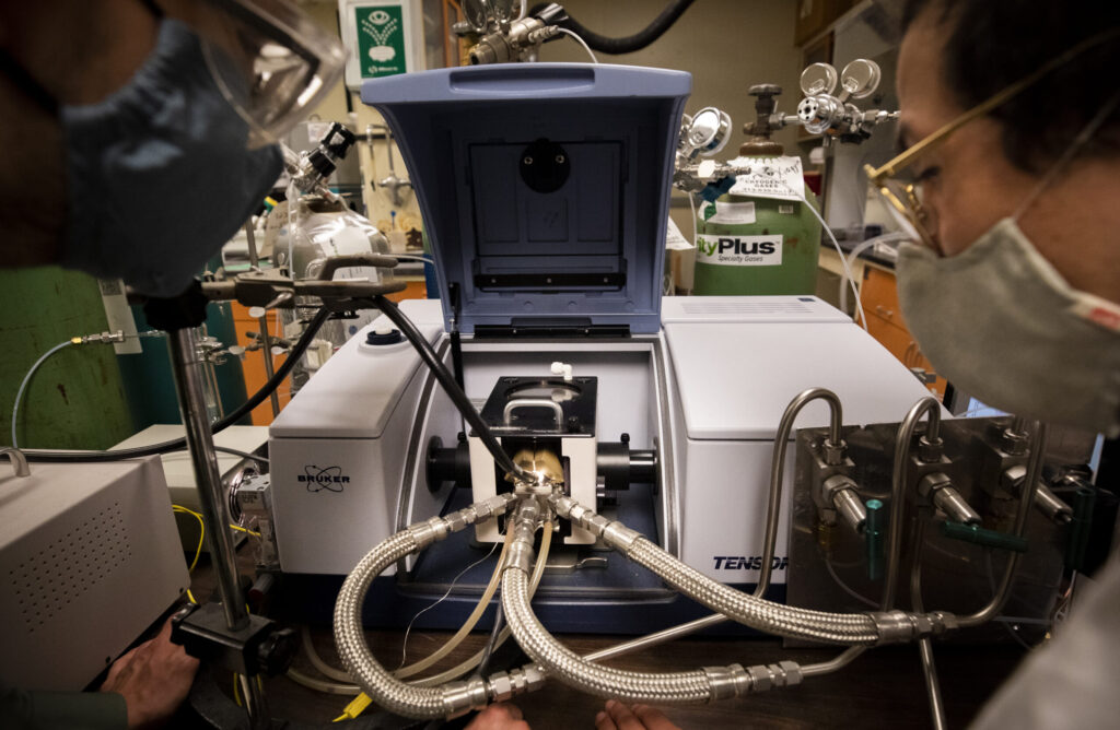 Andrew Gayle, a graduate student research assistant, and Alexander Hill, a graduate student instructor, monitor a new reactor designed to produce ammonia for fertilizer without relying on fossil fuels. Image credit: Robert Coelius, Michigan Engineering
