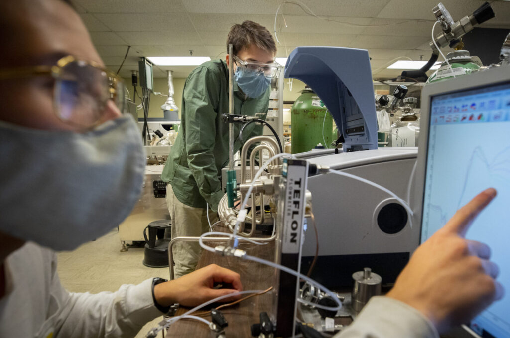 Andrew Gayle, a graduate student research assistant, and Alexander Hill, a graduate student instructor, monitor a new reactor designed to produce ammonia for fertilizer without relying on fossil fuels. Image credit: Robert Coelius, Michigan Engineering