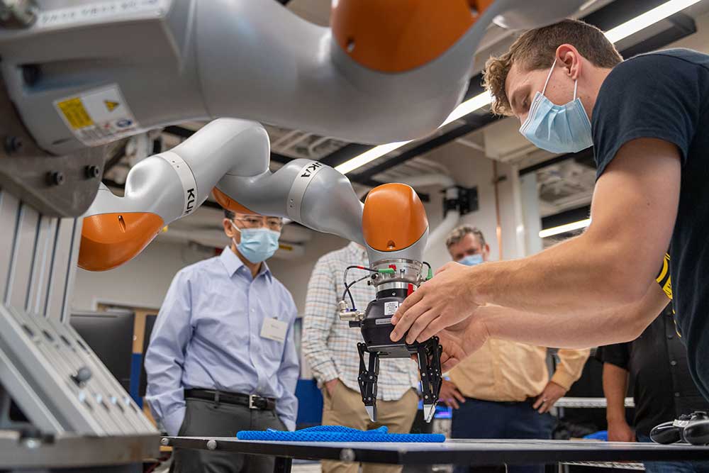 Peter Mitrano demonstrates a rope manipulation experiment. Software that he and Berenson developed can expand training data sets for challenges like rope manipulation, doubling the success rate of the robot. Image credit: Daryl Marshke, Michigan Creative