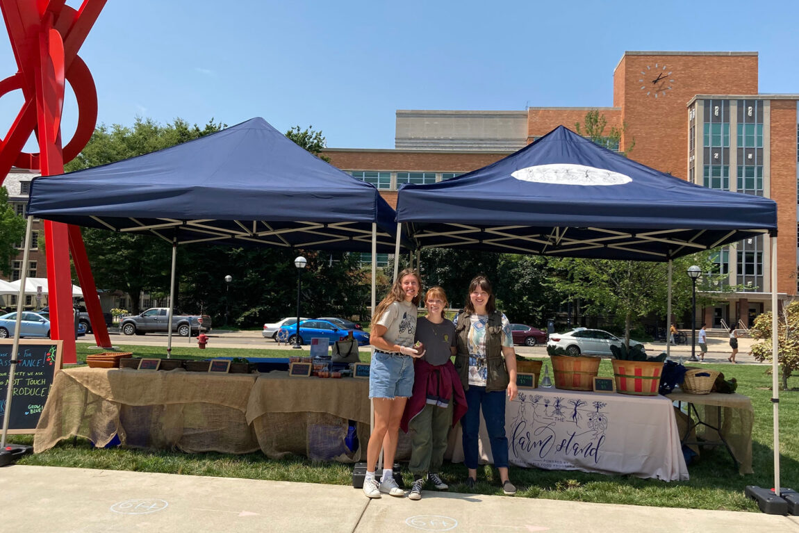 Photo of three students in front of the Farm Stand.