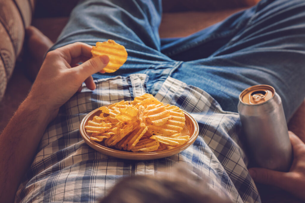 A man eating chips and drinking beer. Image credit: iStock