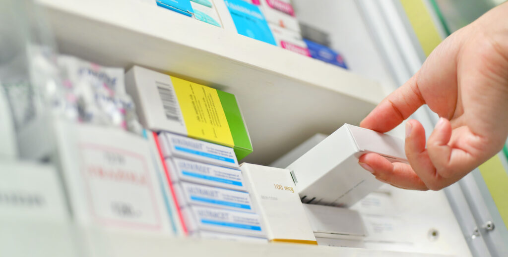 Closeup pharmacist hand holding medicine box in a hospital pharmacy. Image credit: iStock