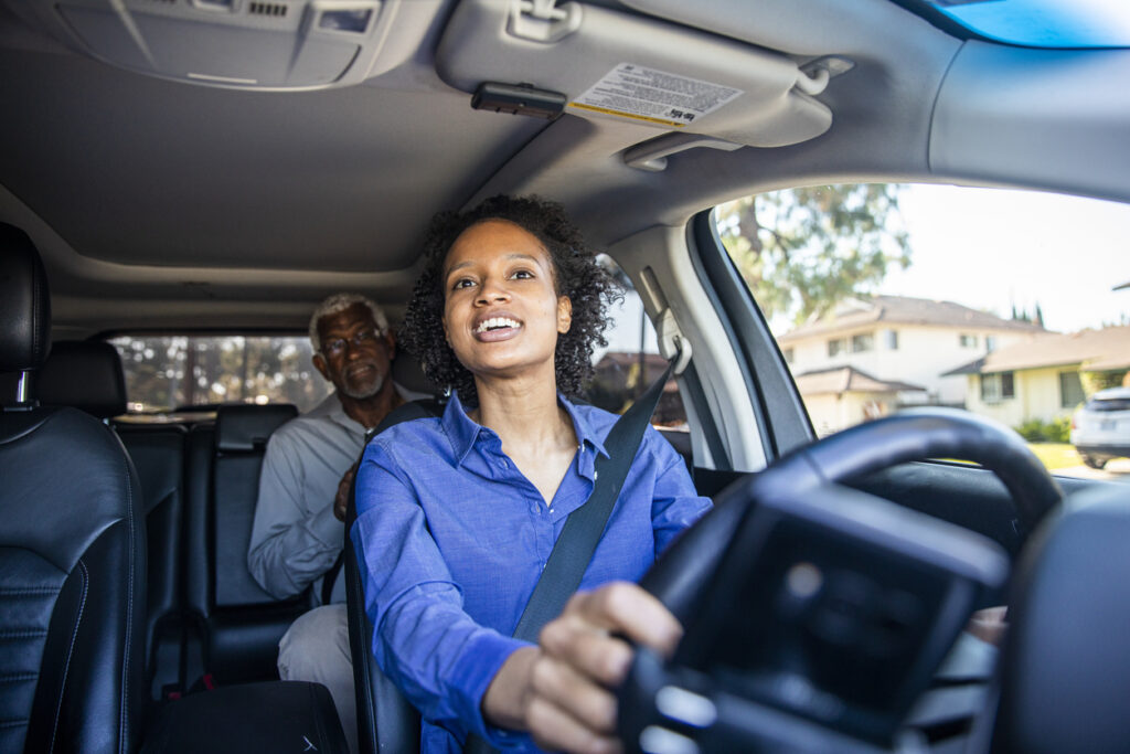 A young woman drives a passenger in her car. Image credit: iStock