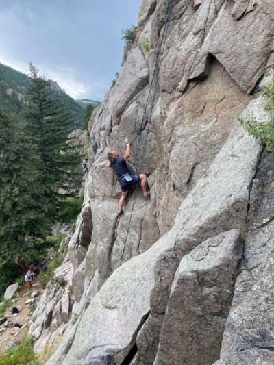 A photo of a man climbing the side of a rock formation.