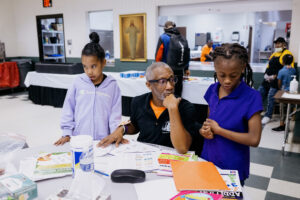 Assistant site director and dance instructor Thomas Butler helps students with homework. Image credit: Erin Kirkland, Michigan Photography