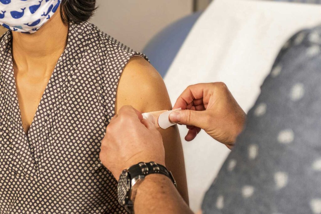 In this 2020 photograph, captured inside a clinical setting, a bandage has been placed on the injection site of a patient, who just received an influenza vaccine. Image credit: CDC