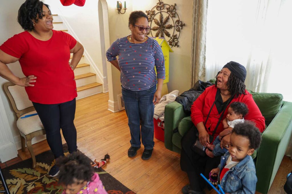 Karlita Johnson, the hub's outreach manager, left, and Samara Ethridge, the community engagement manager, center, greet new arrivals. Image credit: Jeremy Marble