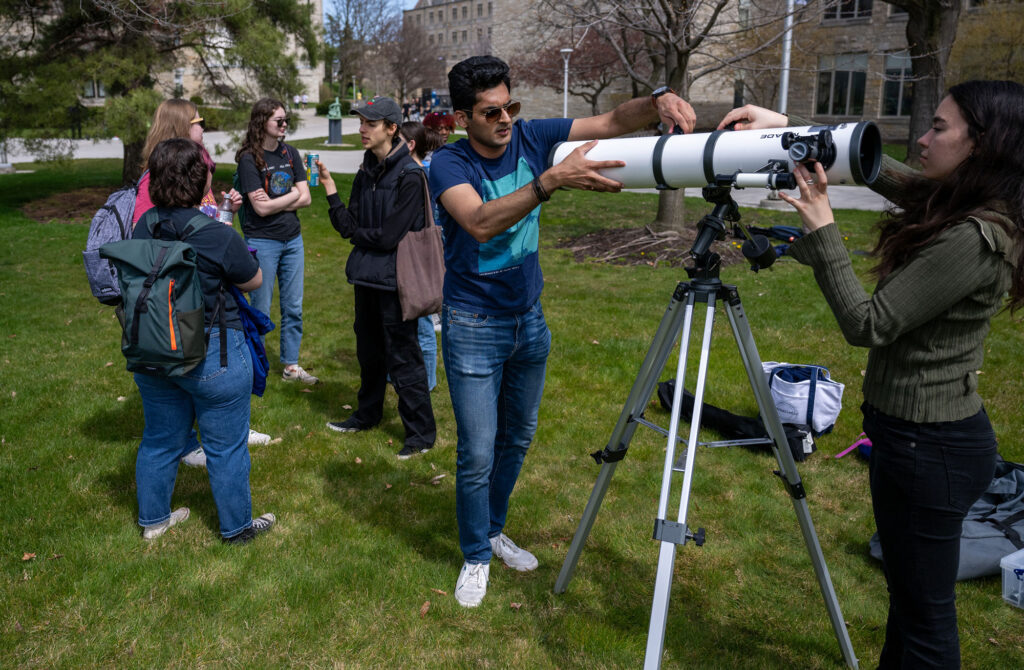 Photo of two students setting up a telescope.