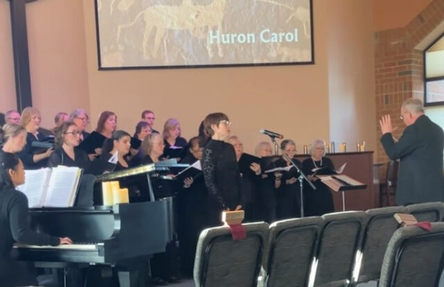 A photo of a woman singing in front of a chrous
