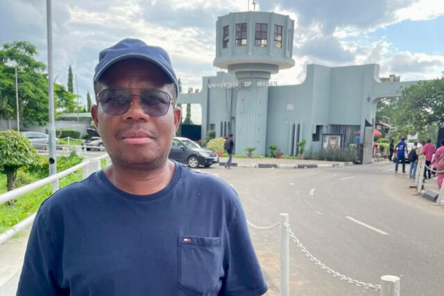Photo of a man in a blue shirt and cap standing in front of a building with a sign that says University of Ibadan