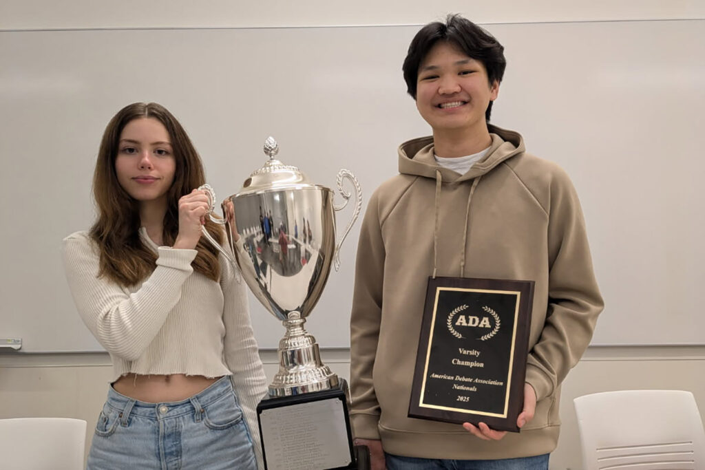 A photo of a woman and a man holding a trophy and a plaque