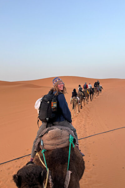 A photo of a woman riding a camel in the desert