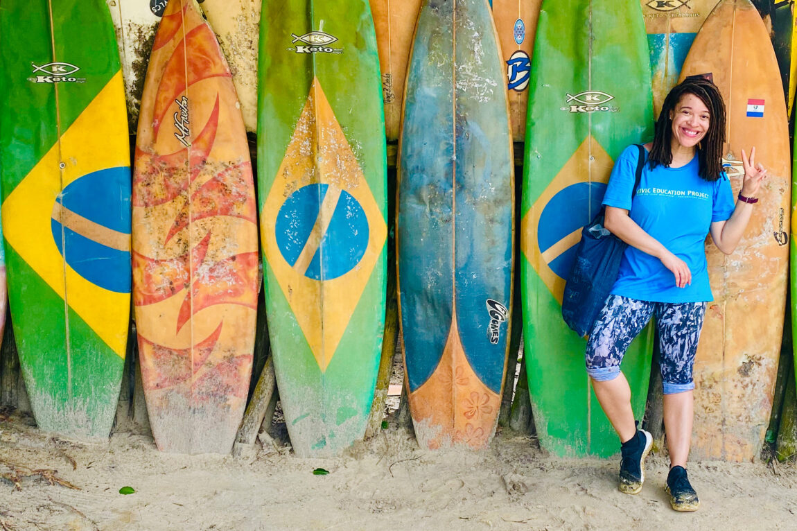 A woman standing in front of several surfboards in the sand