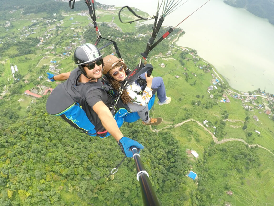 A man and a woman look up while paragliding