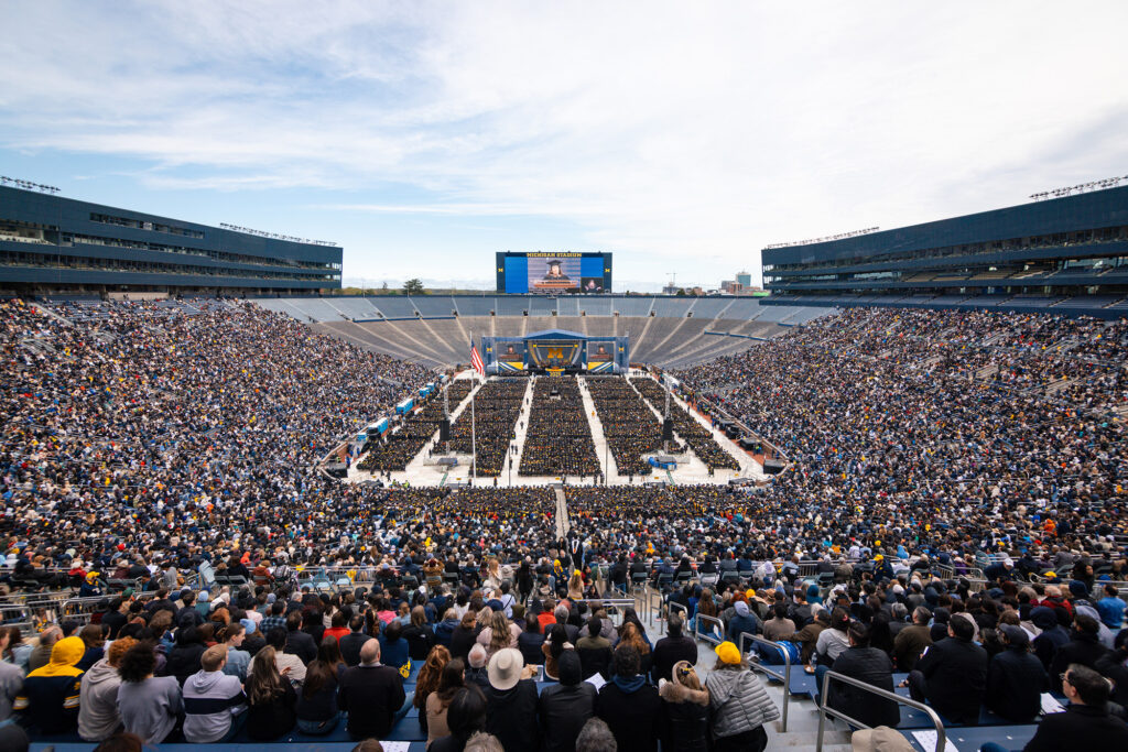 A view from inside a football stadium filled with people attending a graduation ceremony