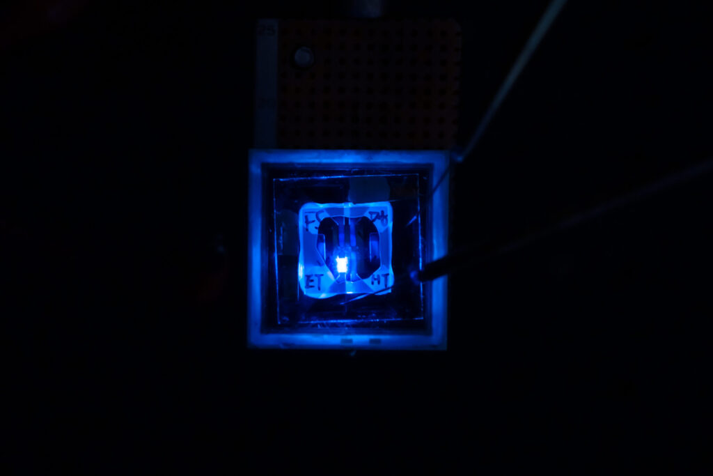 A rectangular blue light shines from a transparent square, its edges marked out by the glow.
