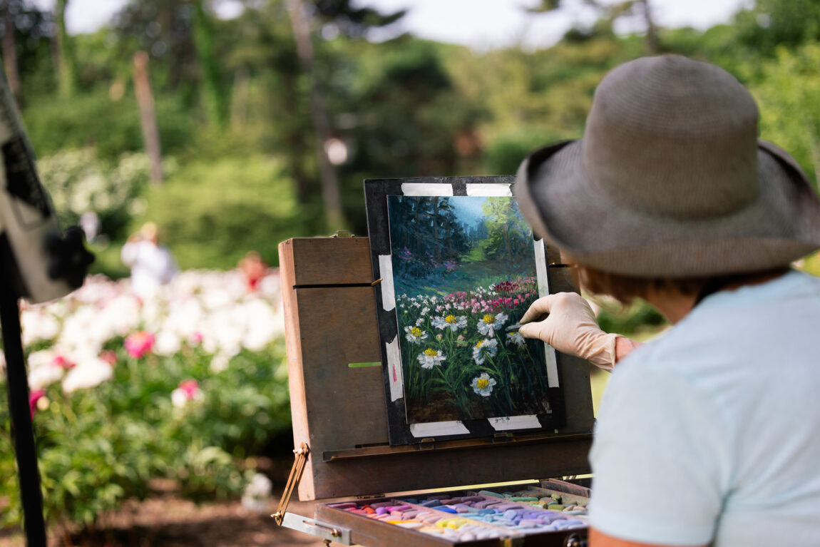 A woman painting flowers on a canvas