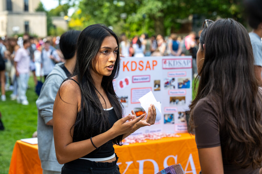 Two people speak to each at an outdoor event