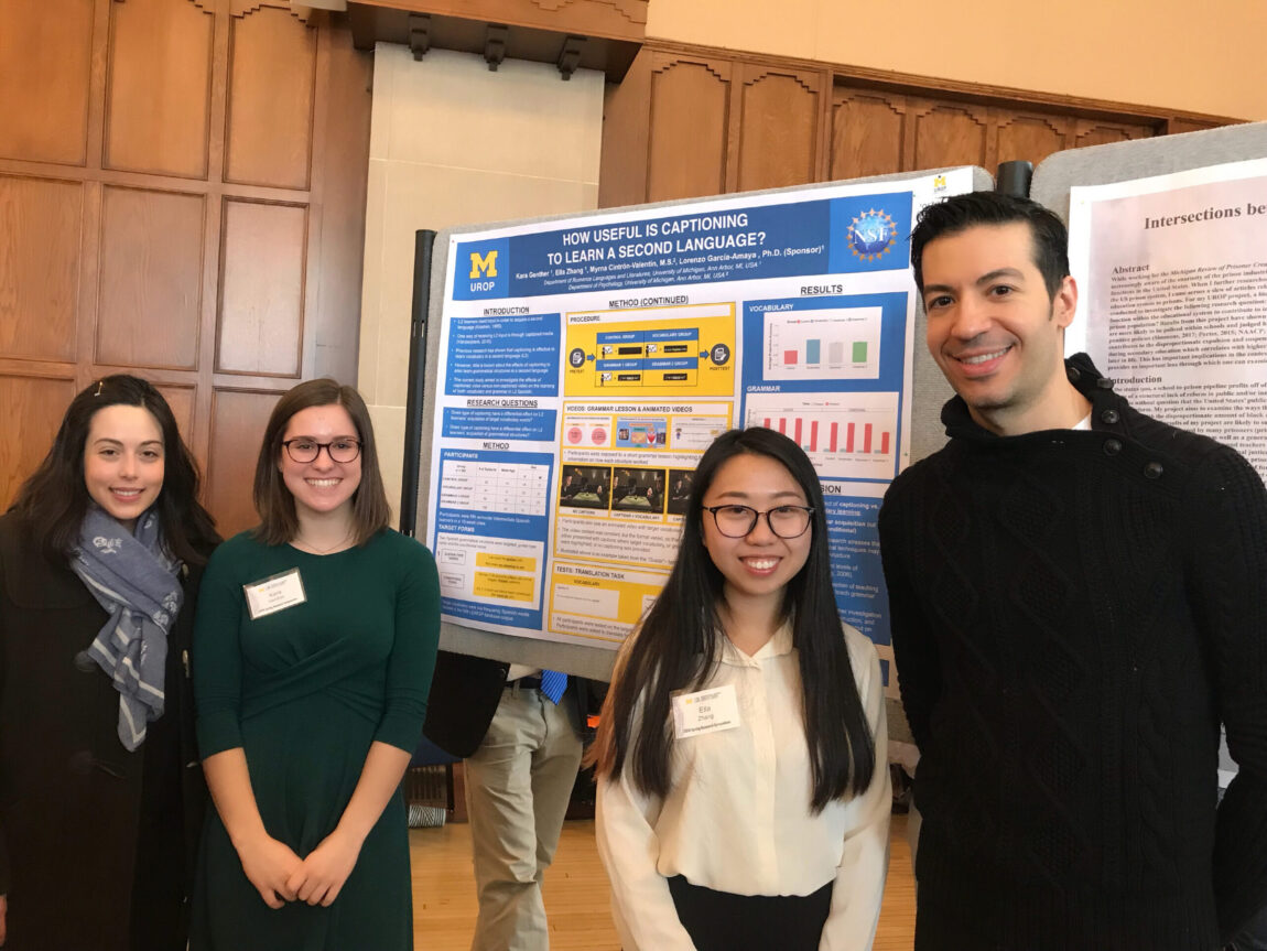 Four people stand before a posterboard