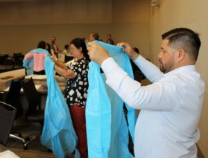 Participants put on hospital gowns in preparation for a hands-on activity. Image credit: Juan Ochoa