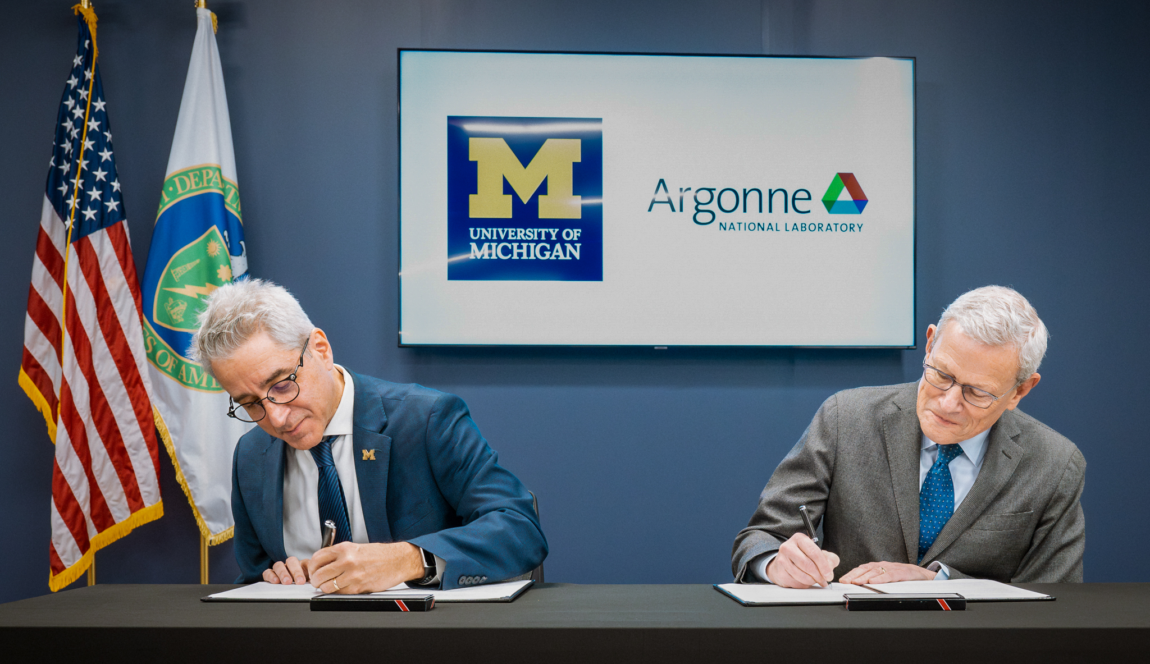 Two men sitting at a table sign papers