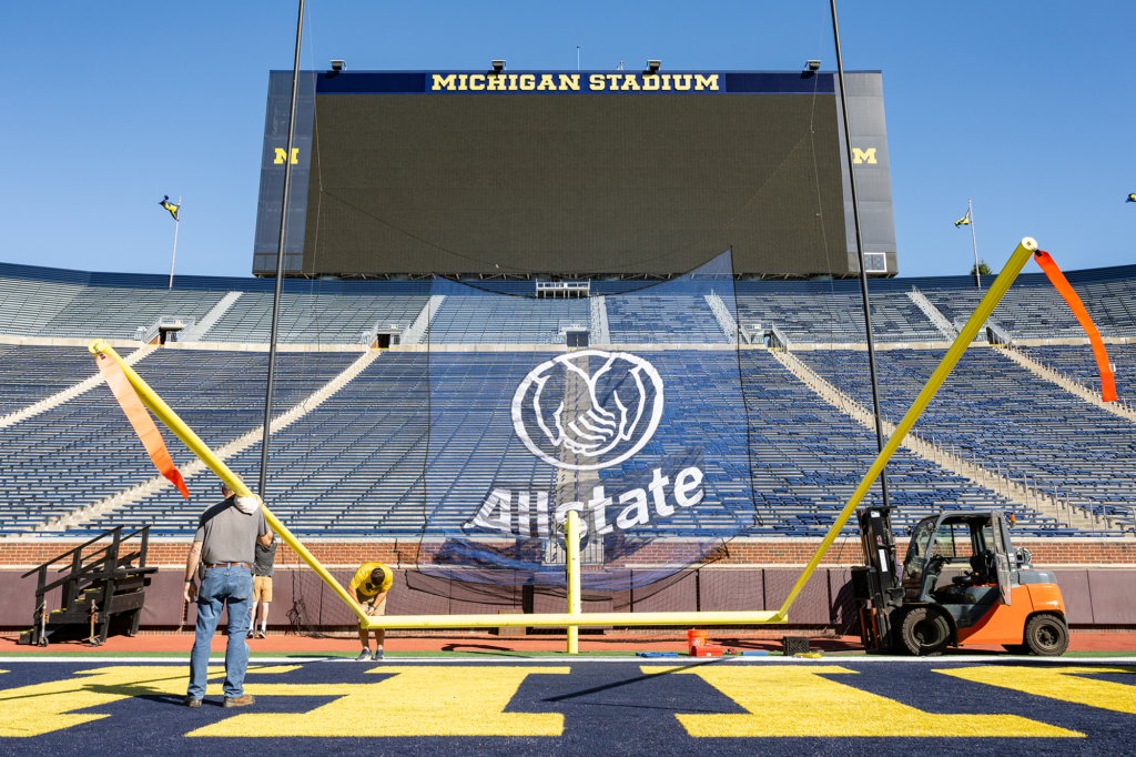 Goal posts are installed at Michigan Stadium under a bright blue sky