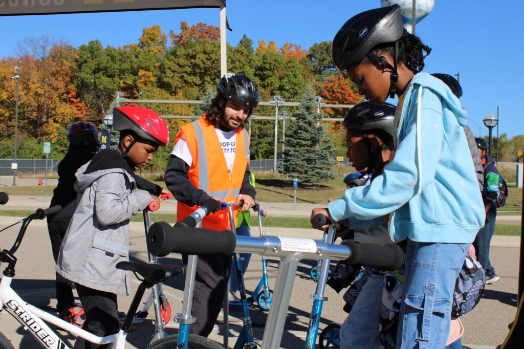 Kids are picking up scooters and preparing to start riding as student volunteer Dylan Hogan explains safety guidelines. Image credit: Juan Ochoa