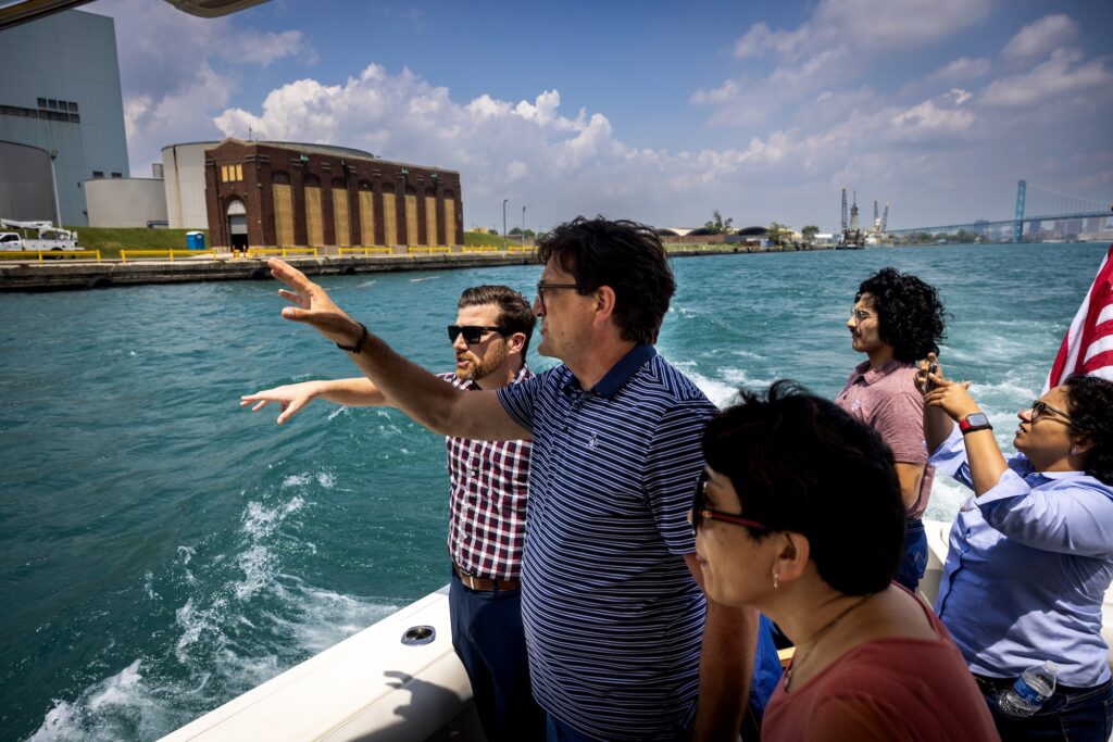 Thomas McKenney (left), a professor of practice of naval architecture and marine engineering, tours the Detroit area's waterfront facilities and infrastructure with Mark Schrupp (second left), executive director of the Detroit Wayne County Port. They are in a boat owned and piloted by Walter and Michael Lytacki, owners of the Michigan Marine Terminal. Employees of the American Bureau of Shipping are also present, including (from center) Xiying Zhang, Robert Fernandez and Veneela Ammula. Image credit: Marcin Szczepanski, Michigan Engineering.