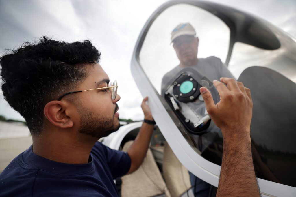 Rohan Madathil (left), a Master's graduate in climate and space sciences and engineering and co-author of the study, helps Nilton Renno (right), a professor of climate and space sciences and engineering, prepare the infrared sensor for a test flight on Renno's personal plane. Image credit: Brenda Ahearn, Michigan Engineering.