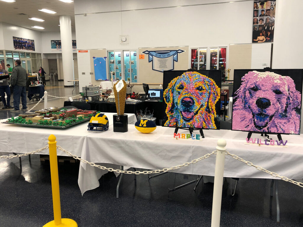 A table with white tablecloths upon which sit many different and colorful LEGO projects