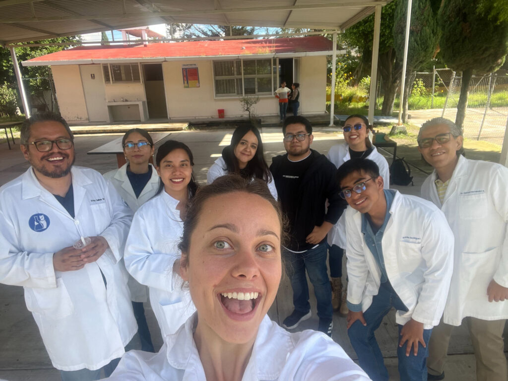 A woman takes a selfie with eight people standing behind her
