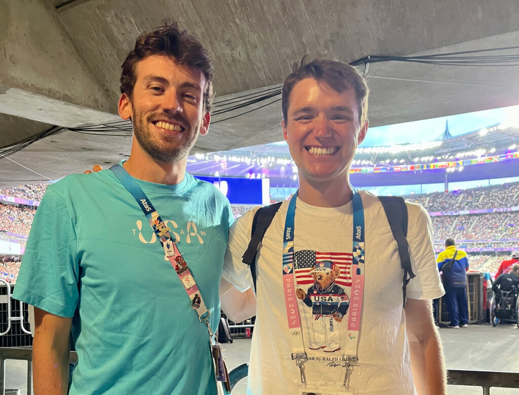 Two men stand side by side and smile
