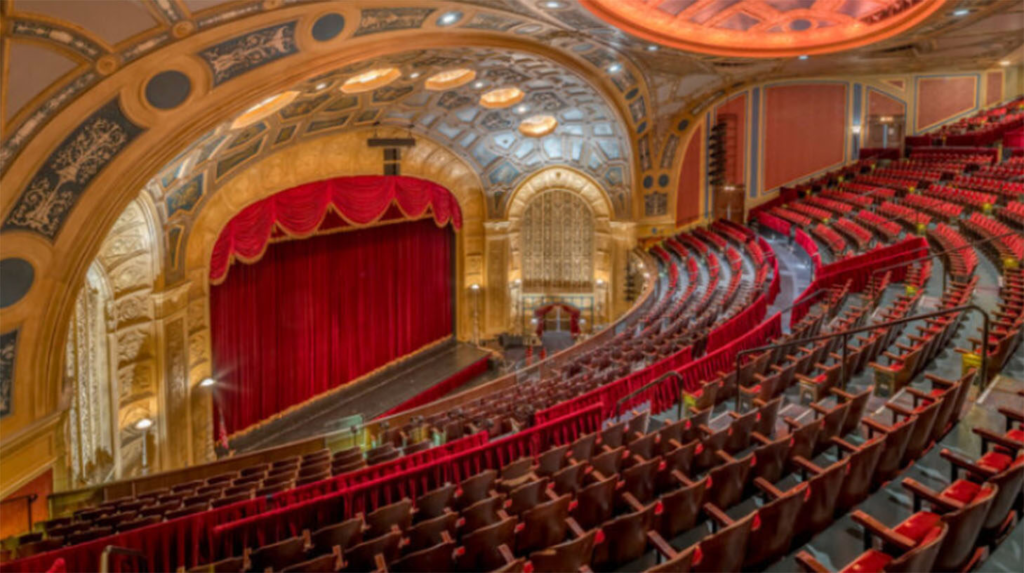An overhead view of an opera house showing rows of seats with a stage and a large red curtain