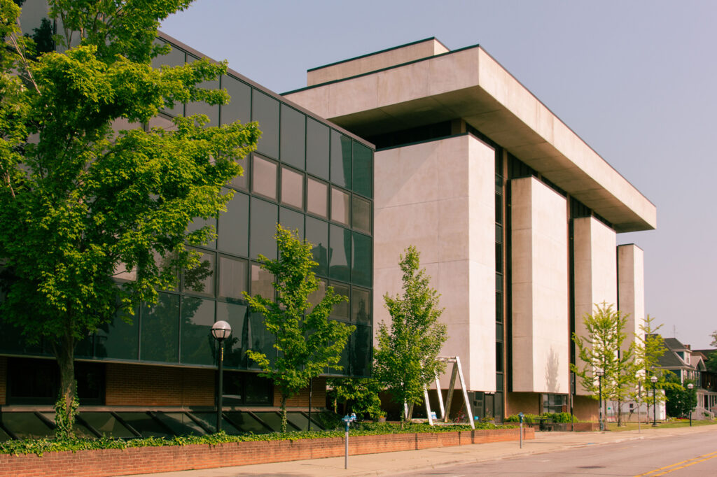 A street view of a building with glass windows and trees in front.
