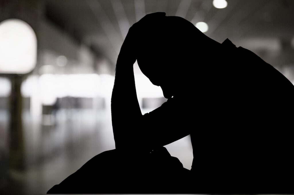 Silhouette of a person with his hand on his head depicting depression. Image credit: Adobe Stock