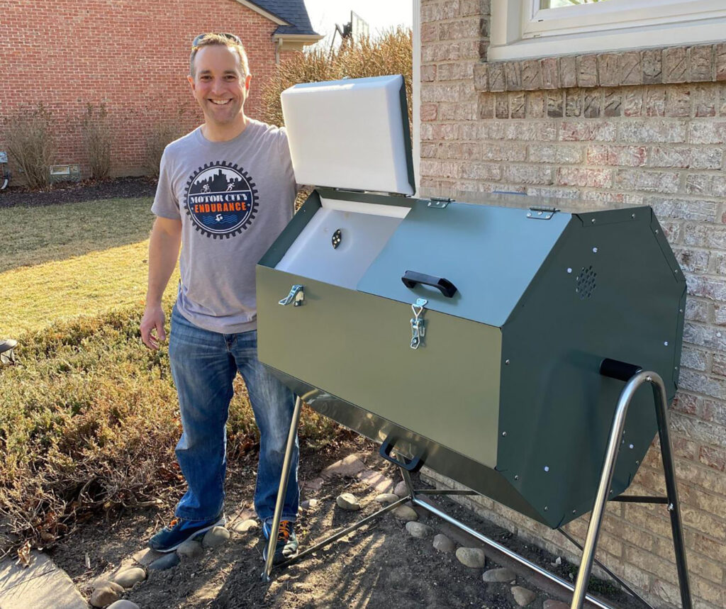 A man stands next to a green composting container