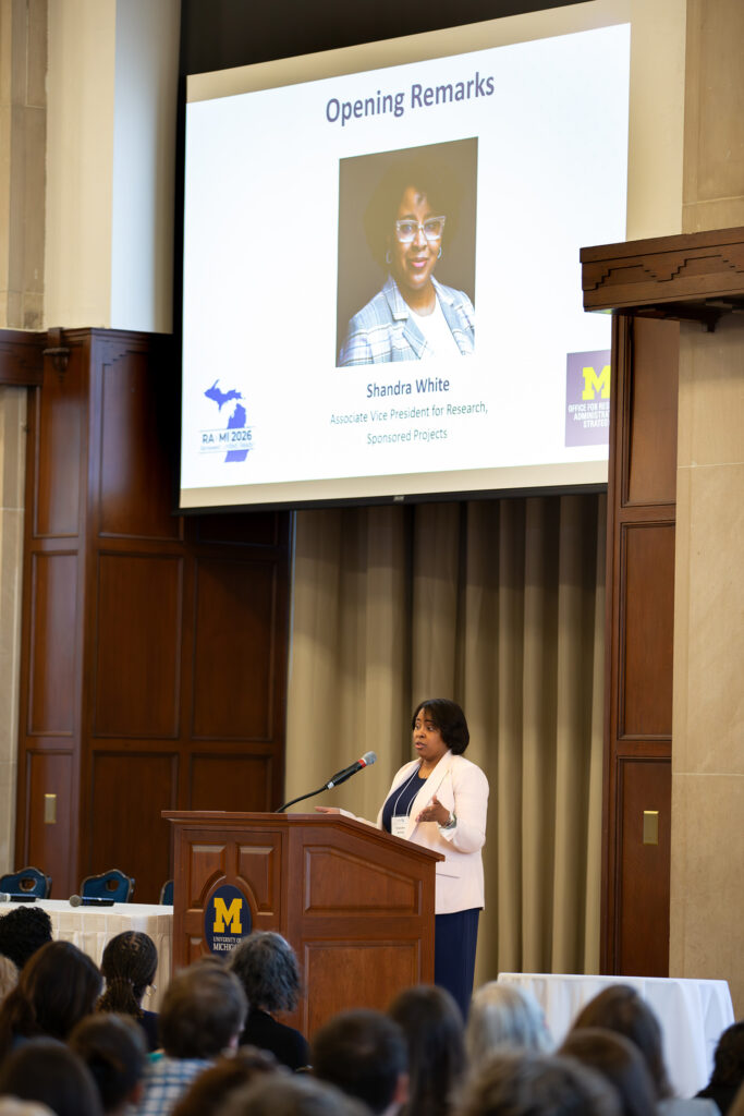 A woman stands at a lectern and speaks to an audience