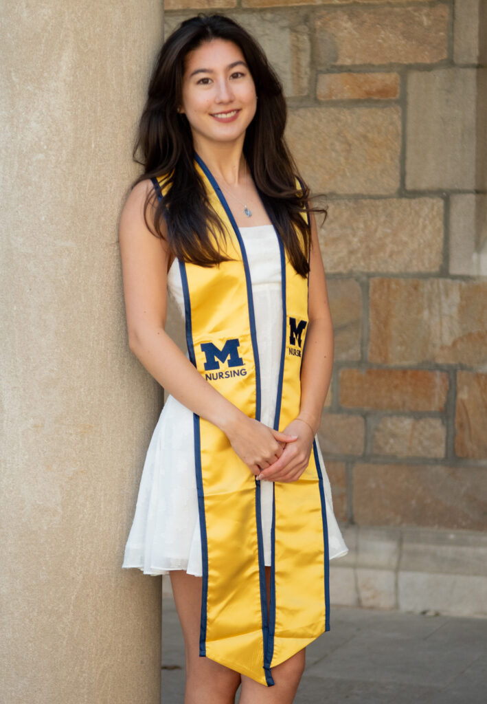 A photo of Sophia Lupton in a white dress and her graduation shawl