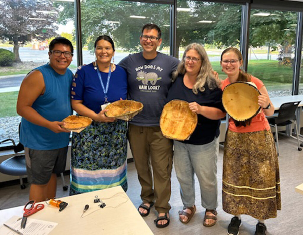 A group of people show off baskets they created at Saginaw Chippewa Tribal College