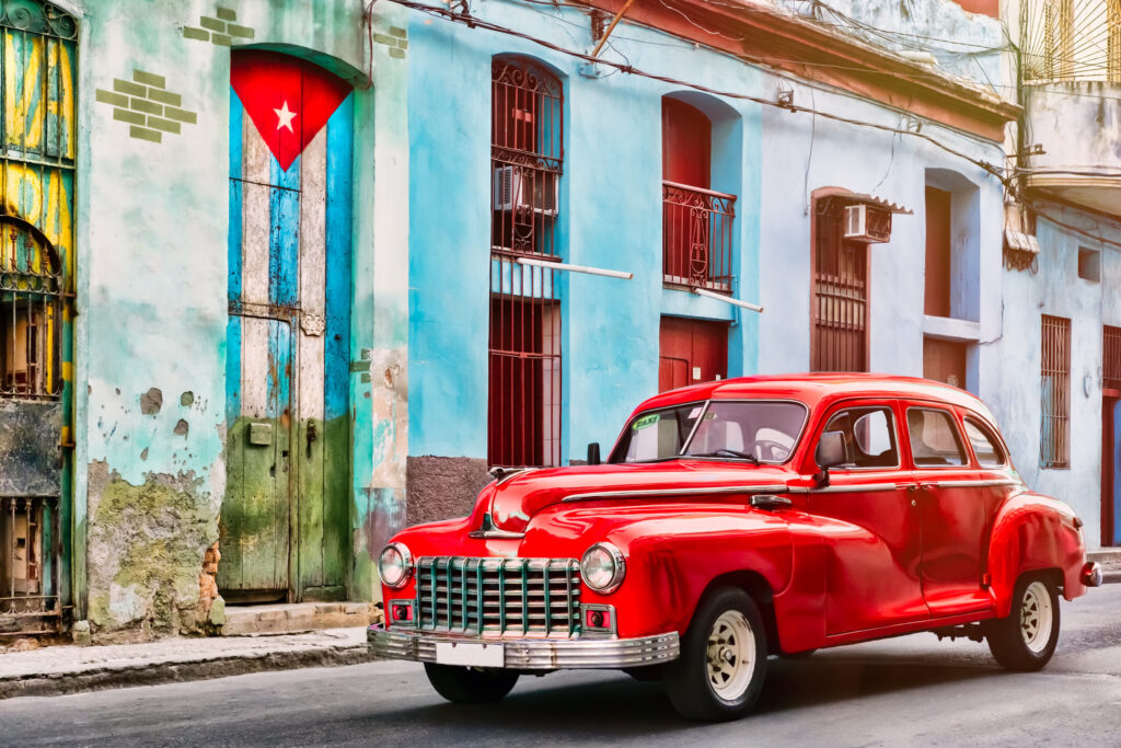 Classic car and old building with the Cuban flag in Old Havana. Image credit: Adobe Stock